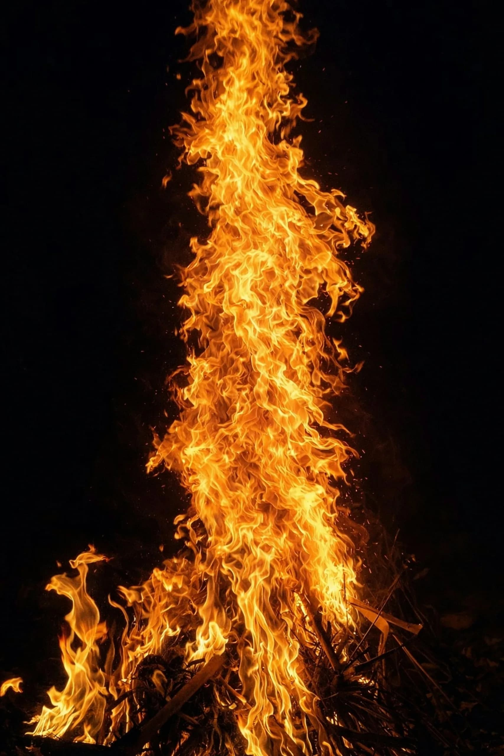 A towering festival bonfire at night